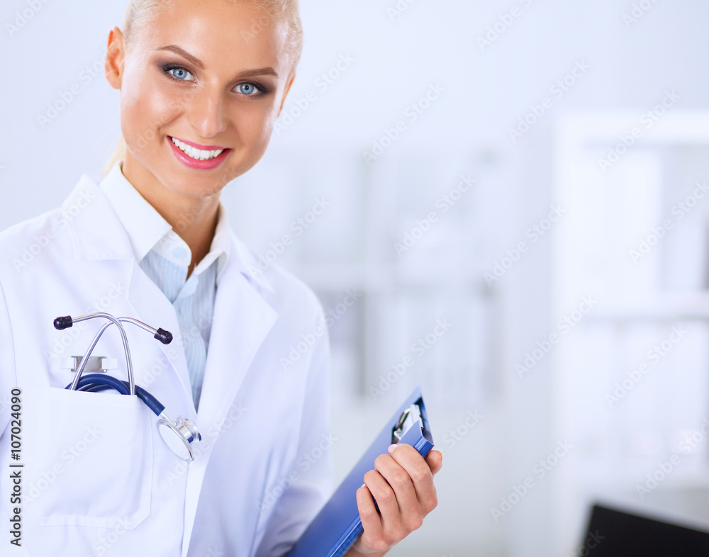 Smiling female doctor with a folder in uniform standing at hospital Smiling female doctor with a folder in uniform standing at hospital