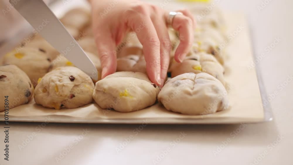 Chef cuts crosses into balls of hot cross bun dough on a baking sheet in preparation for baking. Slow motion, originally recorded in 4K at 60fps. Chef cuts crosses into balls of hot cross bun dough on a baking sheet in preparation for baking. Slow motion, originally recorded in 4K at 60fps.