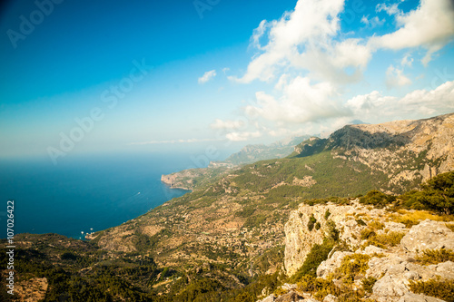 Beautiful landscape view of rocky mountains and clouds on the western part of Mallorca island, Spain. Tramuntana mountains with blue sea in background. Tourist trekking destination in Spain.