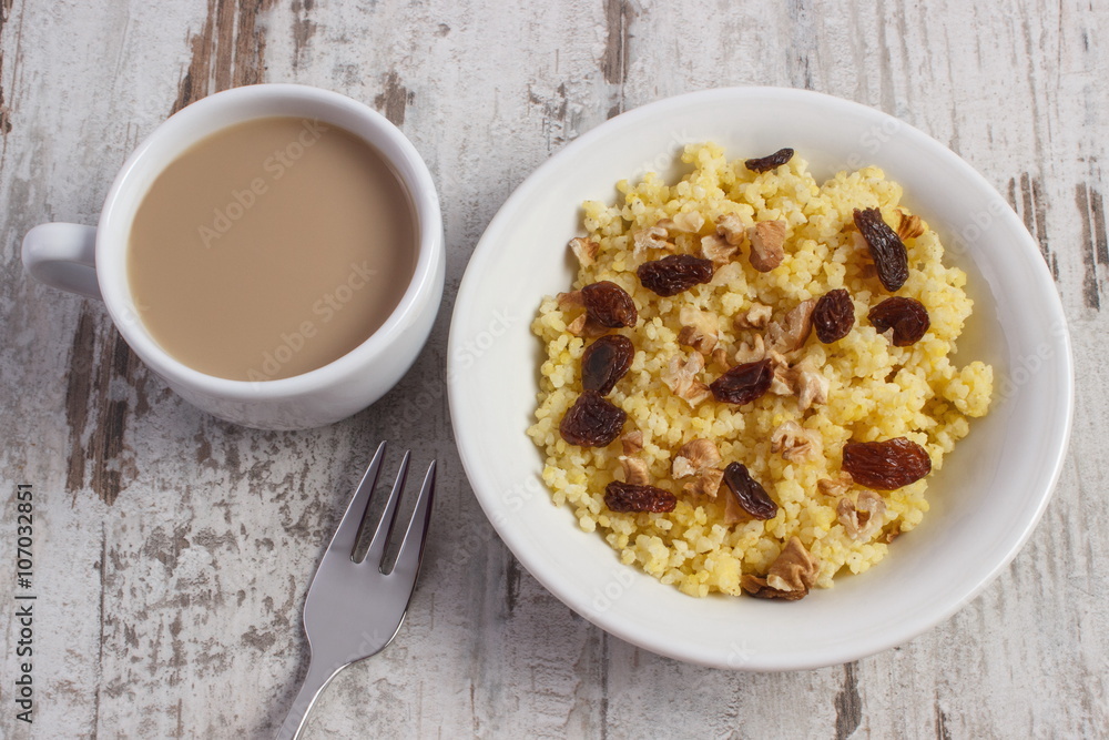 Cooked millet groats on white plate and cup of coffee with milk, healthy food and nutrition Cooked millet groats on white plate and cup of coffee with milk, healthy food and nutrition