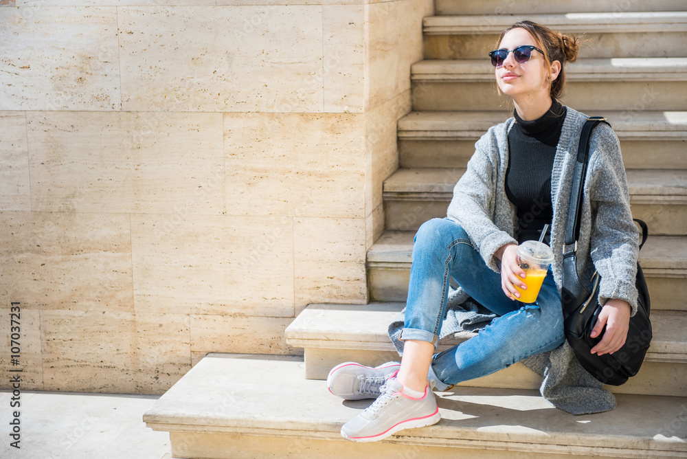 Young beautiful  woman, sitting on the street , drinking smoothie.