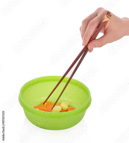 hand pick chopsticks eating in a green plastic bowl on white bac