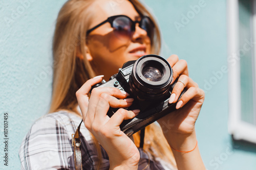 Close up lifestyle details,young hike hipster woman holding retro sunglasses,golden jewelry,warm colors.holding vintage retro camera on her hands,stylish classic accessorizes