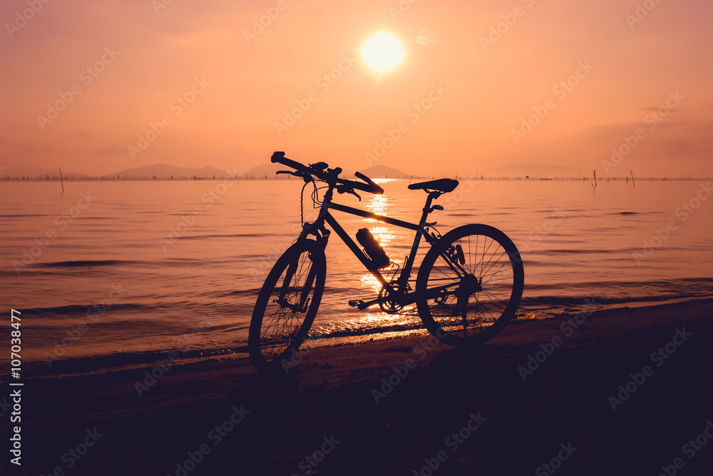 Silhouette of bicycle on the beach against colorful sunset