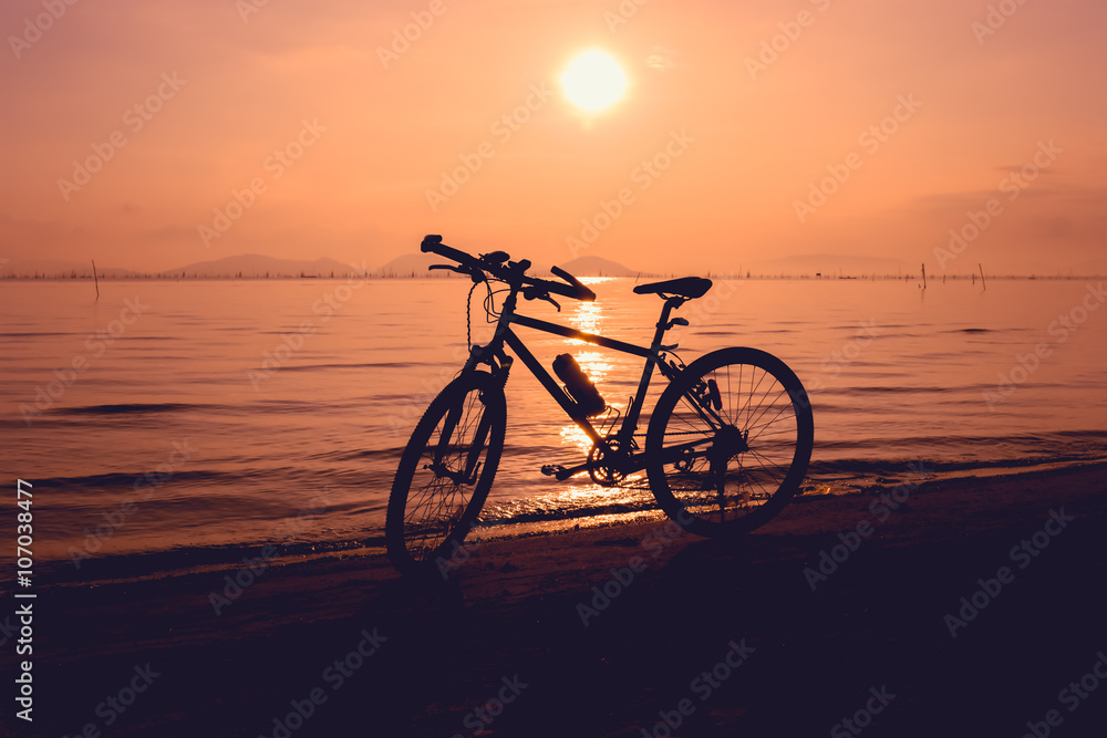 Fototapeta premium Silhouette of bicycle on the beach against colorful sunset
