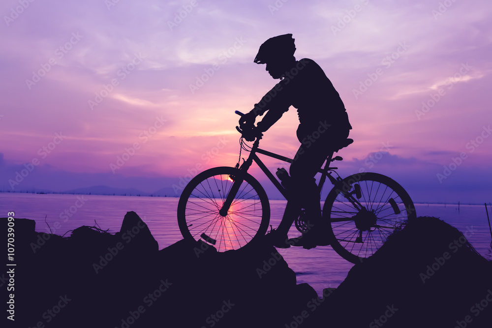 Obraz premium Healthy lifestyle. Silhouette of bicyclist riding the bike at seaside.