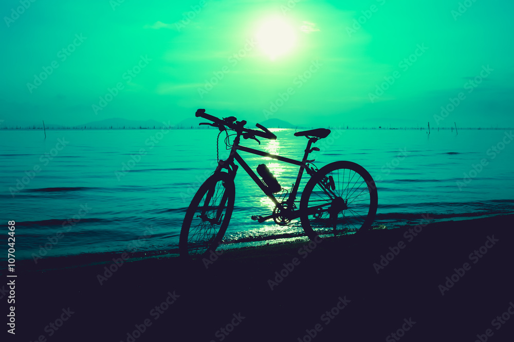 Silhouette of bicycle on the beach against colorful sunset in the sky