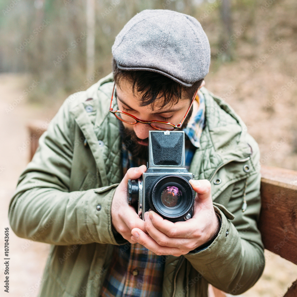 Young man bearded with film photocamera in the forest Young man bearded with film photocamera in the forest
