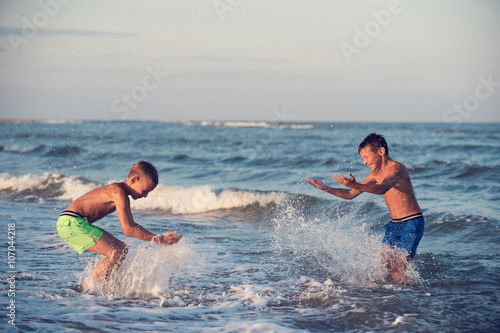 Two boys playing at the beach with water. Big splashes © Valua Vitaly