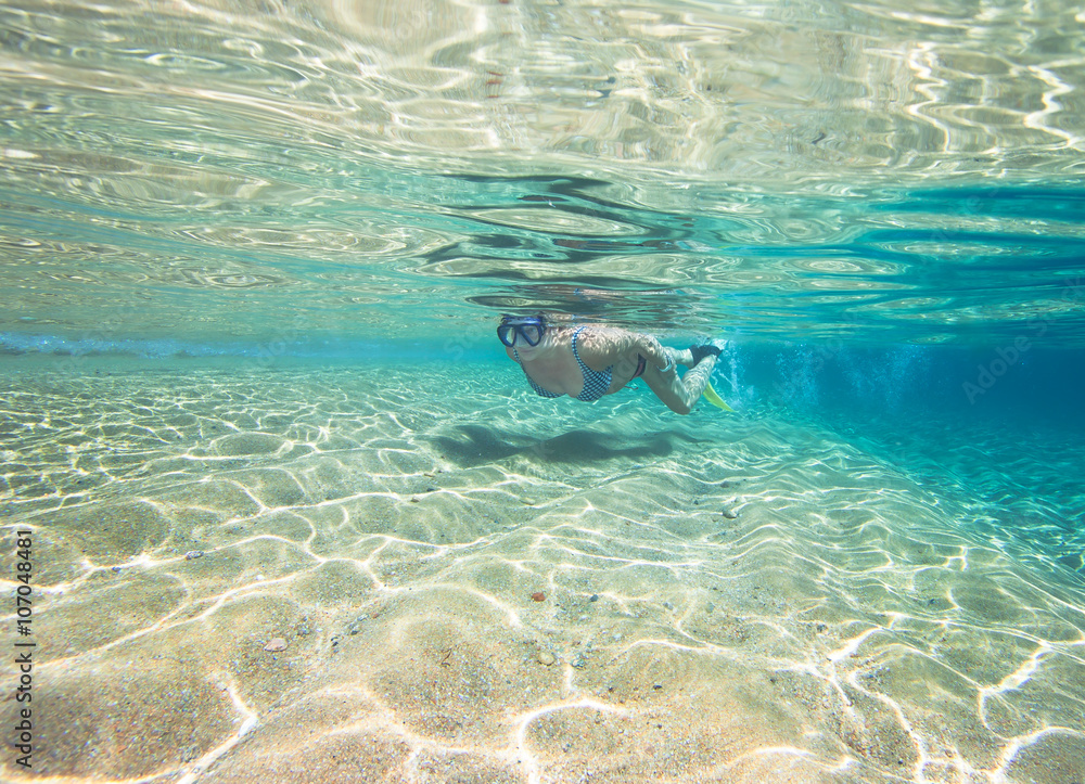 Woman swimming underwater in clear tropical sea
