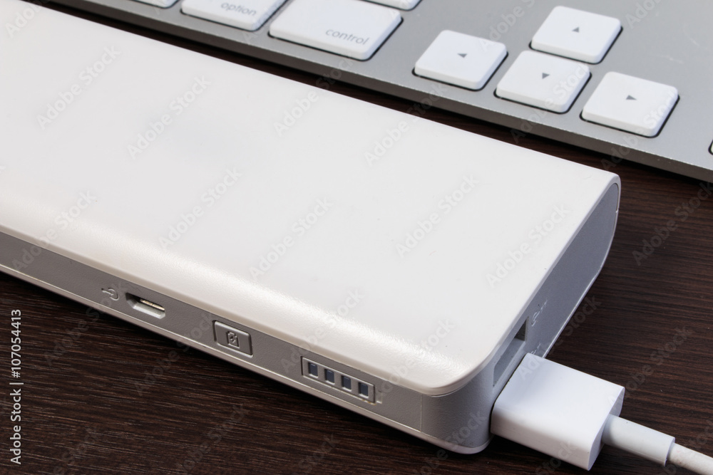 USB cable charger with energy bank on wooden table. USB cable charger with energy bank on wooden table.