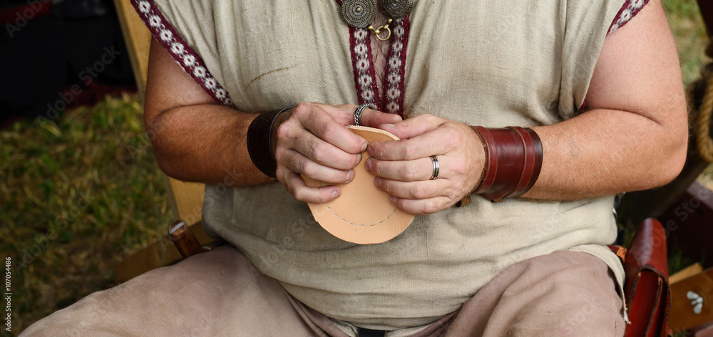 Medieval leatherworker makes leather mug for kitchen decoration