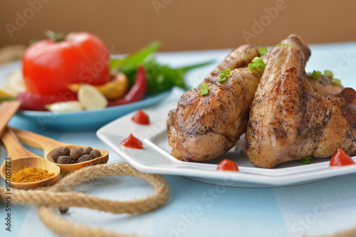 Fried chicken wings and legs on a white plate, with spices