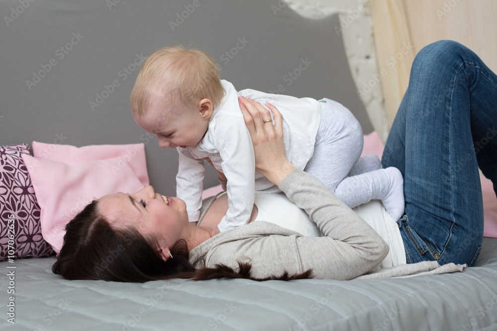 Funny playful mum with baby toddler at home