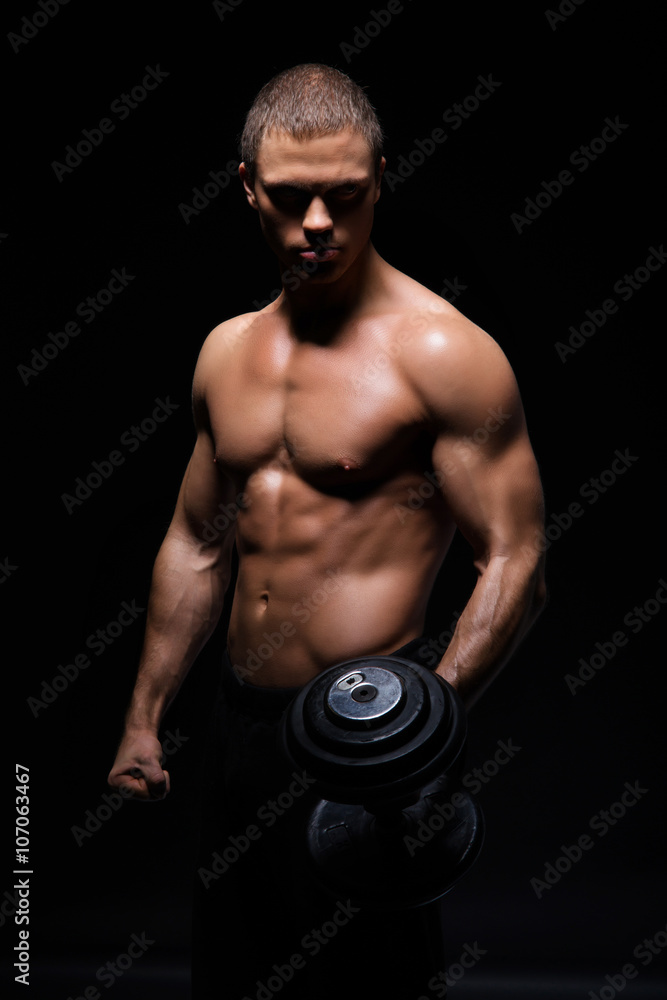 Strong, fit and sporty bodybuilder man with a dumbbell