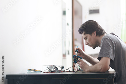 Young man making an electronic device soldering and adjusting the components