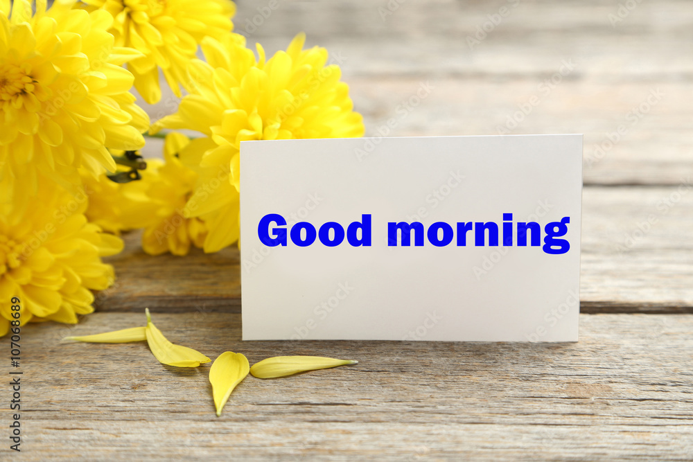 Naklejka premium Yellow chrysanthemum flowers with card on a grey wooden table