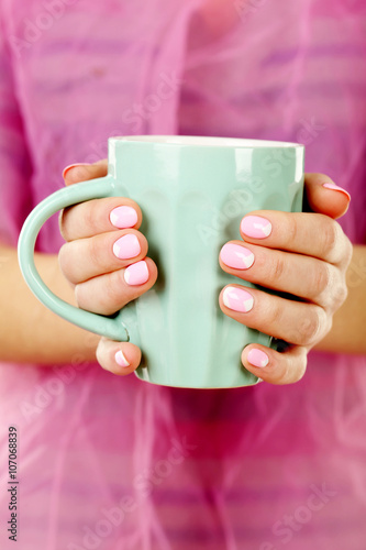 Female hand with manicure holding mint cup