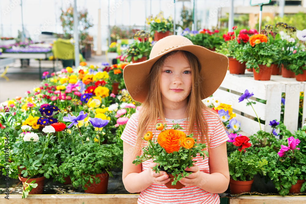 Adorable little girl choosing flowers in garden center