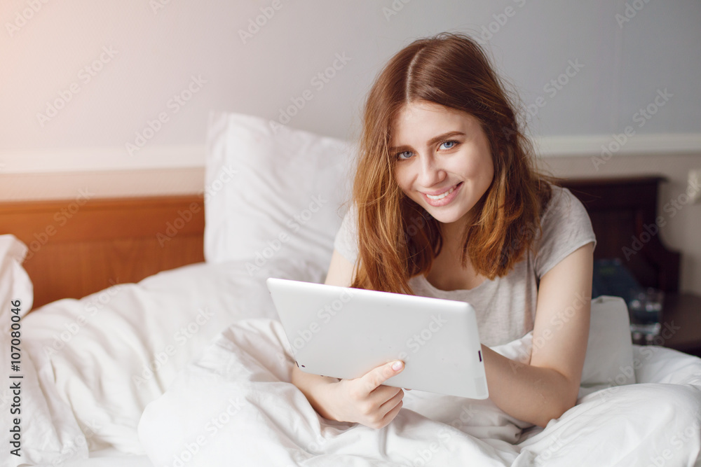 Cheerful smiling girl with pad in bright bedroom Cheerful smiling girl with pad in bright bedroom