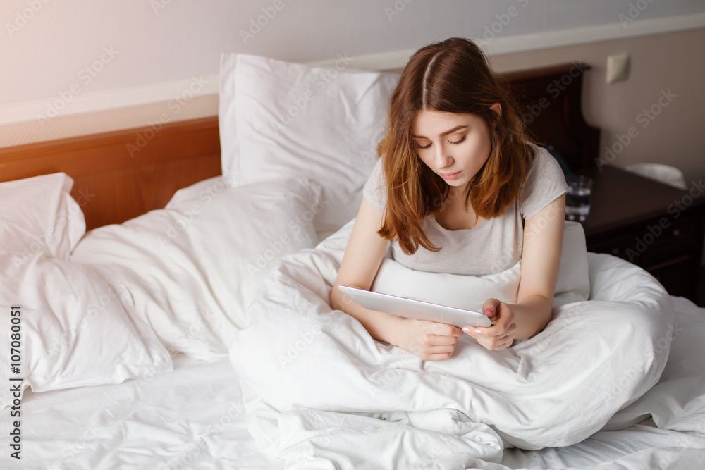 Girl lying on bed home using howing blank tablet screen Girl lying on bed home using howing blank tablet screen