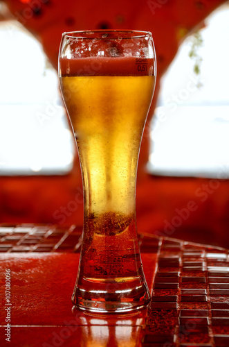 Glass of cold beer on a red table photo