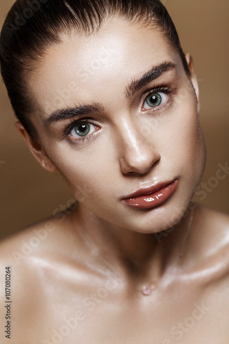 Strobing or Highlighting makeup. Closeup portrait of beautiful girl with strobing highlighter powder. Nice Glow. Perfect retouch. Studio photo beige background. Wet body effect photo
