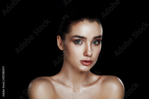 Beauty Portrait of Pretty Woman with Strobing Makeup. Wet Body Effect. Strobing or Highlighting makeup technique. Professional Retouch and Studio Photo. Ideal commercial concept. Black background