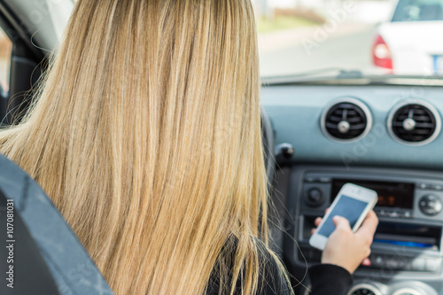 Frau tippt auf Handy während Autofahrt