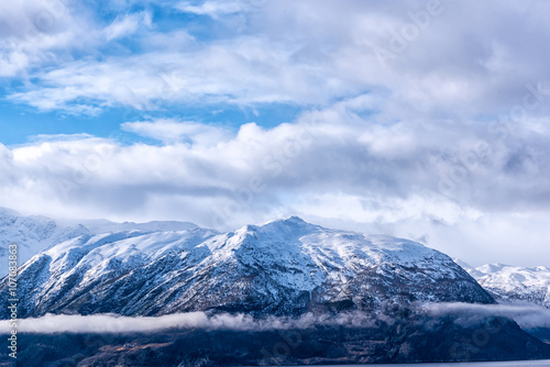 Snow caped mountain range under a blue cloudy sky