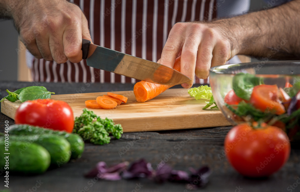 Male hands cutting vegetables for salad Male hands cutting vegetables for salad