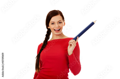 Beautiful student woman pointing up with a big pencil