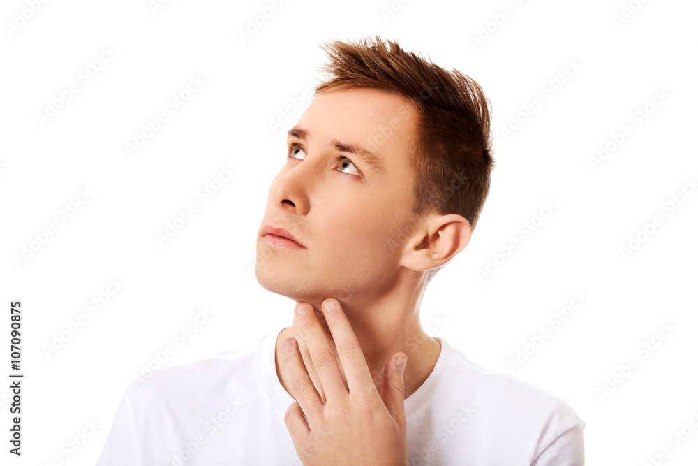 Young thinking man looks up with hand near face Young thinking man looks up with hand near face