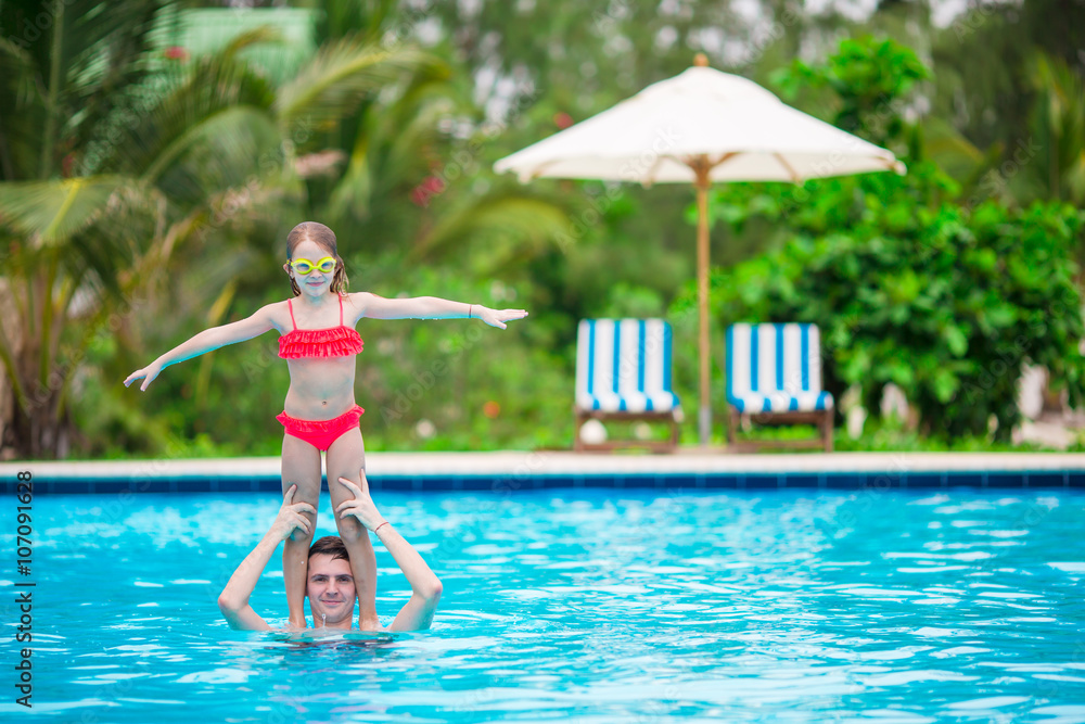 Little girl and father having fun in outdoors swimming pool