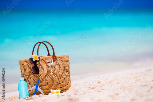 Beach consept - straw bag, hat, sunglasses and suncream bottle on white beach
