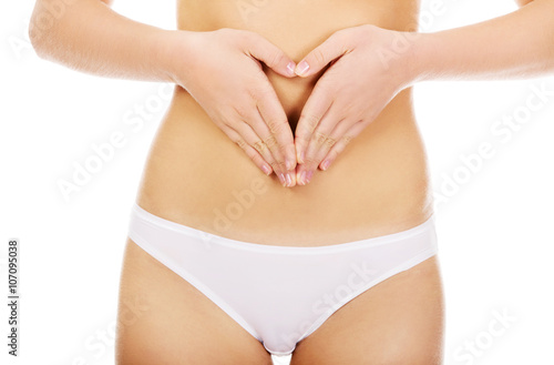 Young woman in white panties making heart shape on her belly