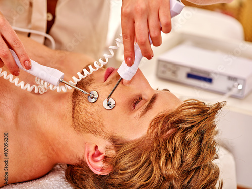 Man gets revitalizing electric facial peeling hydradermie at beauty salon.  photo