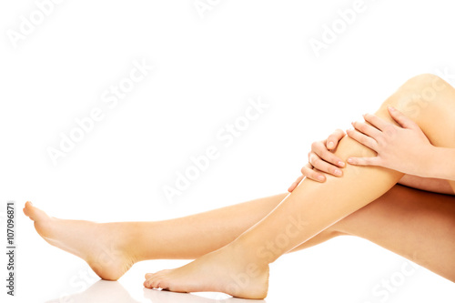 Young woman sitting on the floor and touching her legs