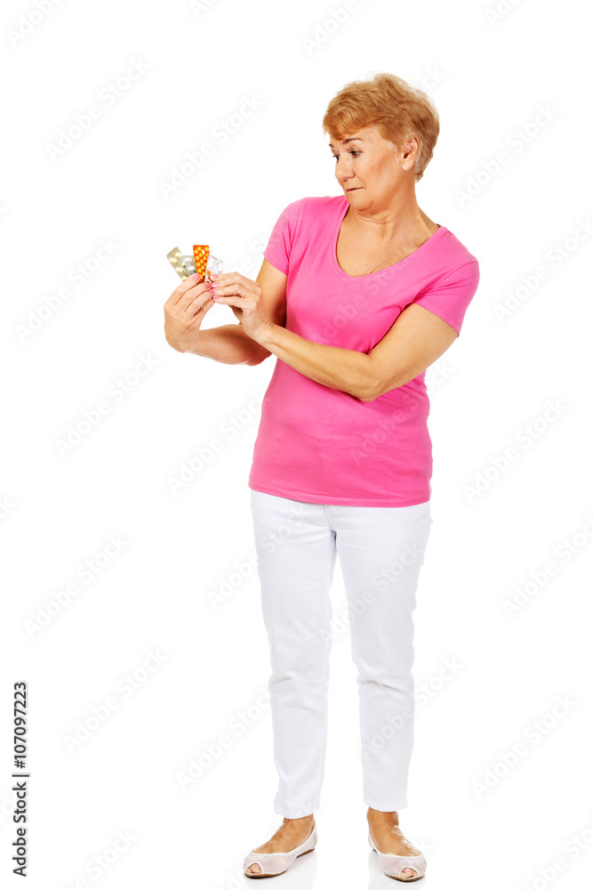 Shocked senior woman holding few tablets package Shocked senior woman holding few tablets package