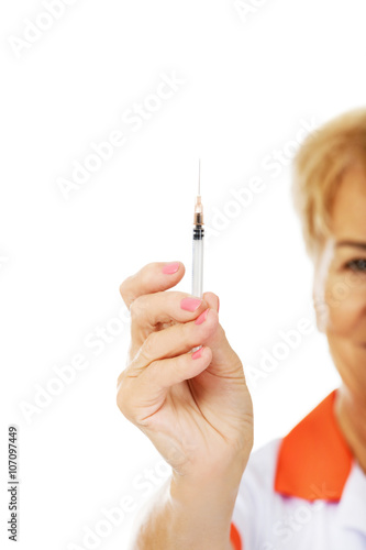 Smile elderly female doctor or nurse holds syringe