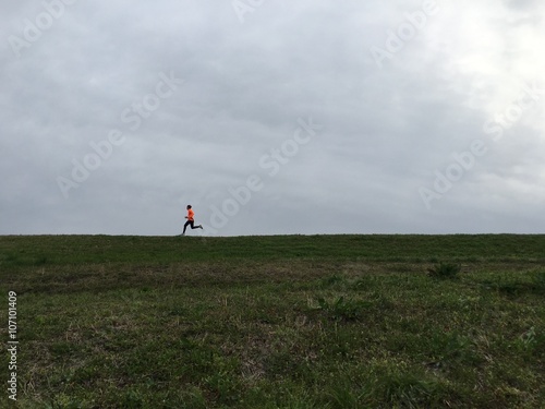 Photography Man running along top of river embankment