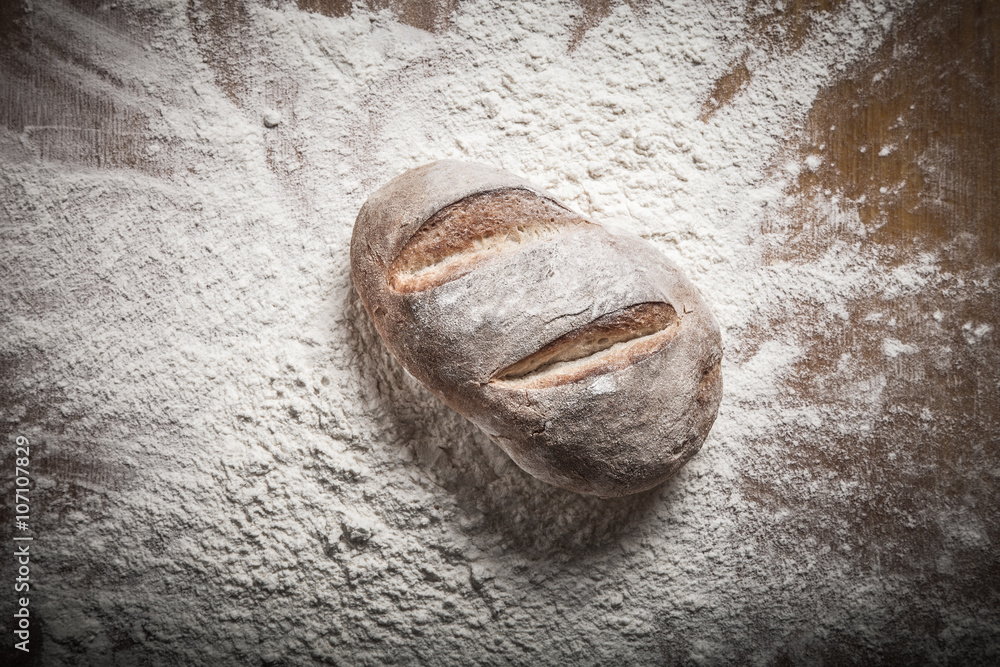 Naklejka premium Fresh home bread fell in a heap of flour. Toned