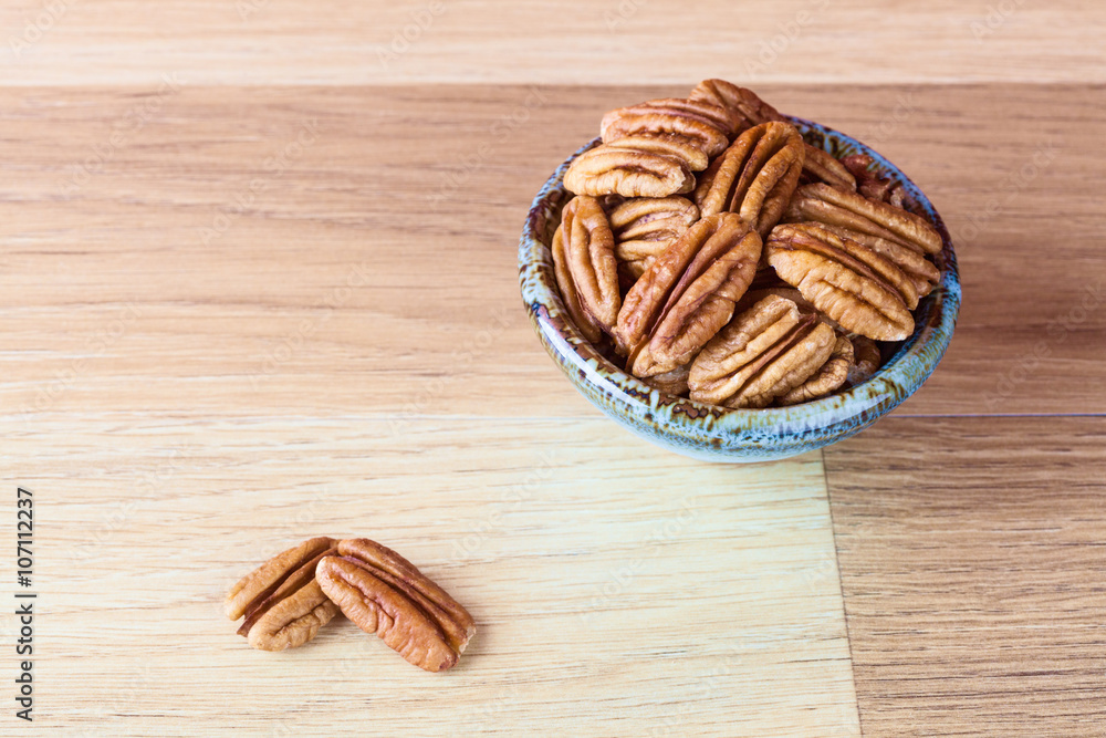 Pecans on wooden surface and in ceramic bowl with copy space. Shallow depth of field. Pecans on wooden surface and in ceramic bowl with copy space. Shallow depth of field.