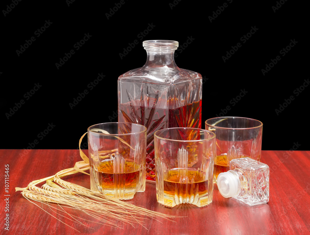 Decanter and three glasses with whiskey, several barley spikes Decanter and three glasses with whiskey, several barley spikes