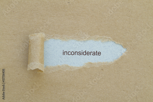 inconsiderate word written under torn paper. photo