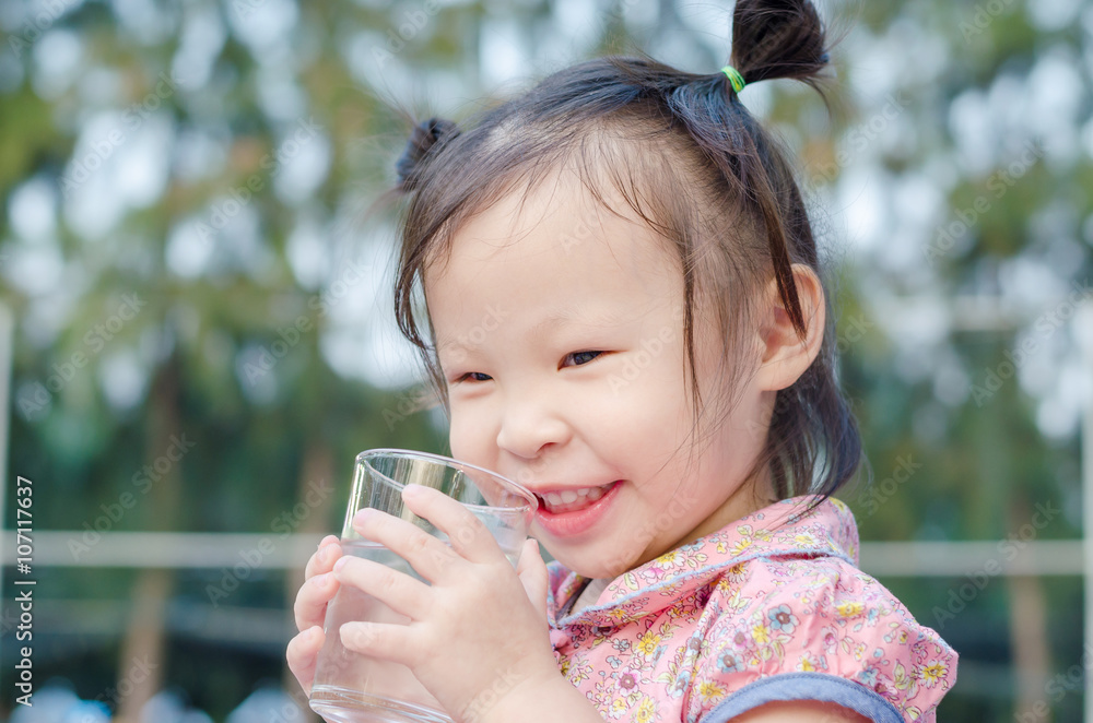 Little Asian girl smiles after drinking water from glass Little Asian girl smiles after drinking water from glass