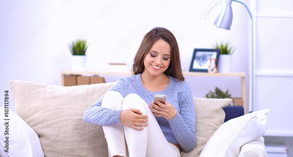 Pretty girl using her smartphone on couch at home in the living room Pretty girl using her smartphone on couch at home in the living room