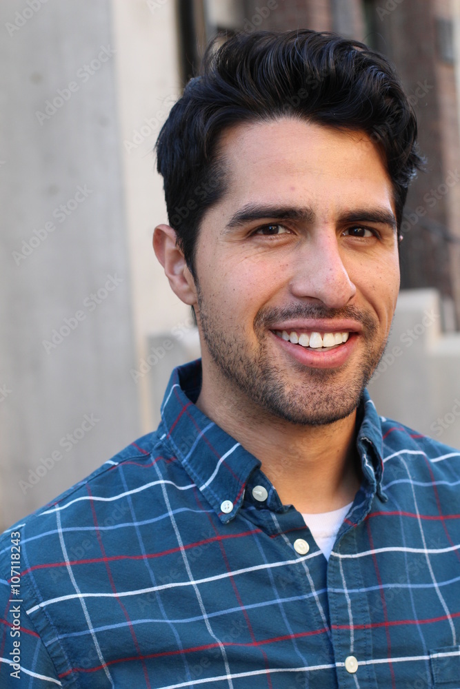 Obraz premium Young and attractive latino male smiling in the city
