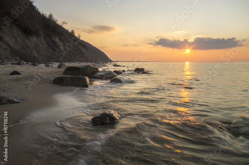 Klif i plaża morska w świetle zachodzącego słońca