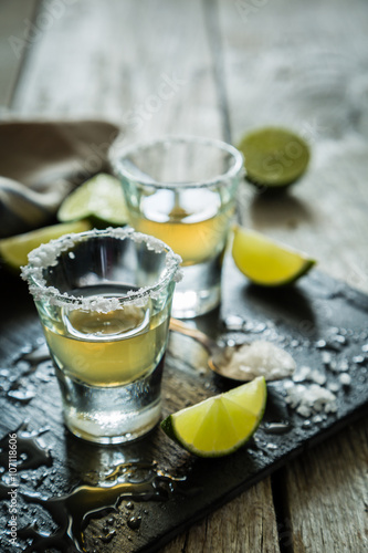 Gold tequila shots on rustic wood background
